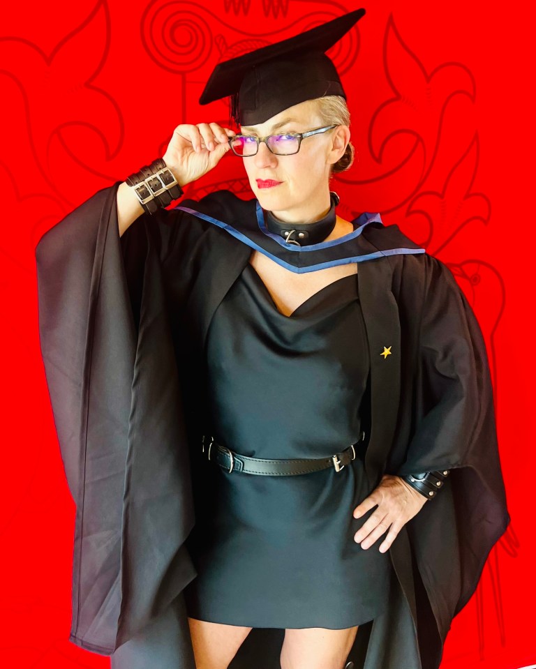 Lynne in graduation cap and gown against a red background
